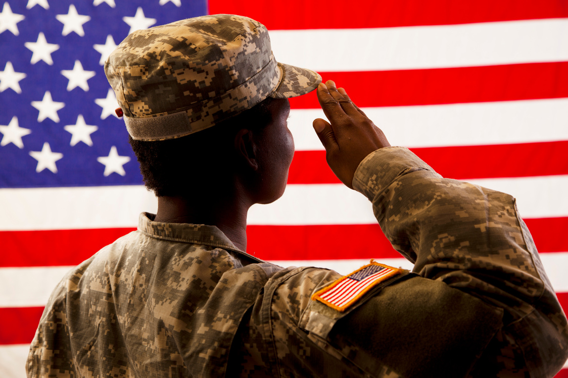 African American military woman salutes USA flag.