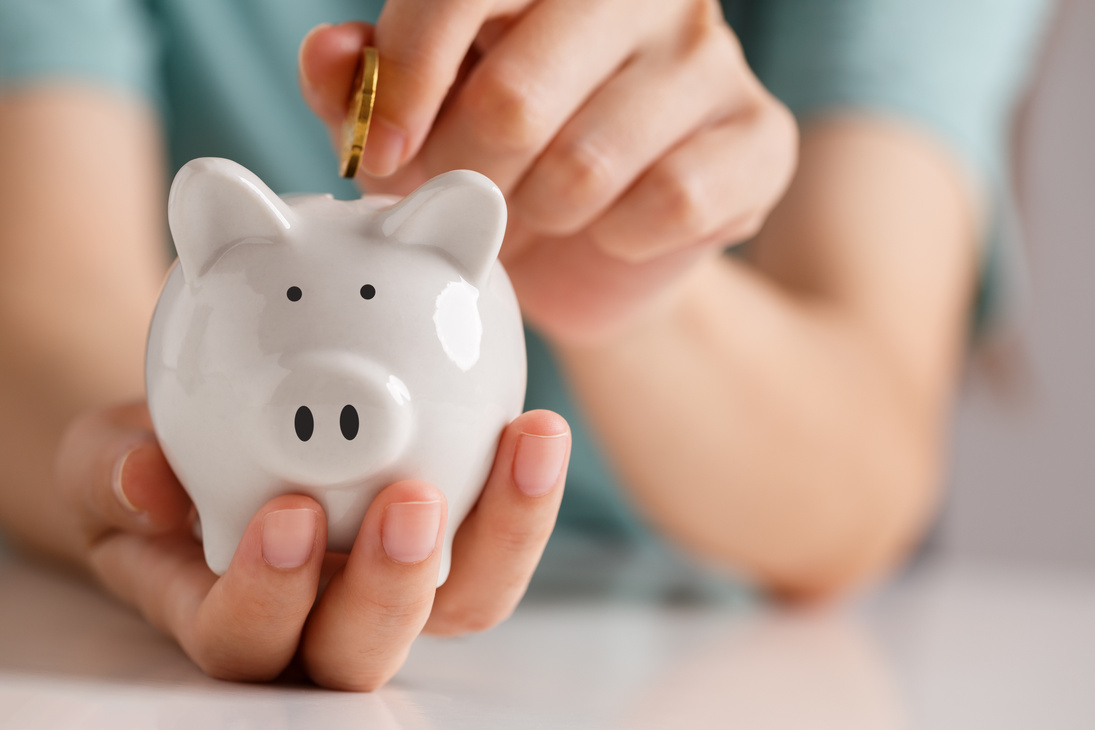 Female hand putting money into piggy bank for saving money.