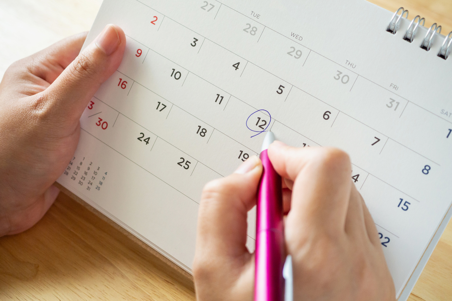 calendar page with female hand holding pen on desk table